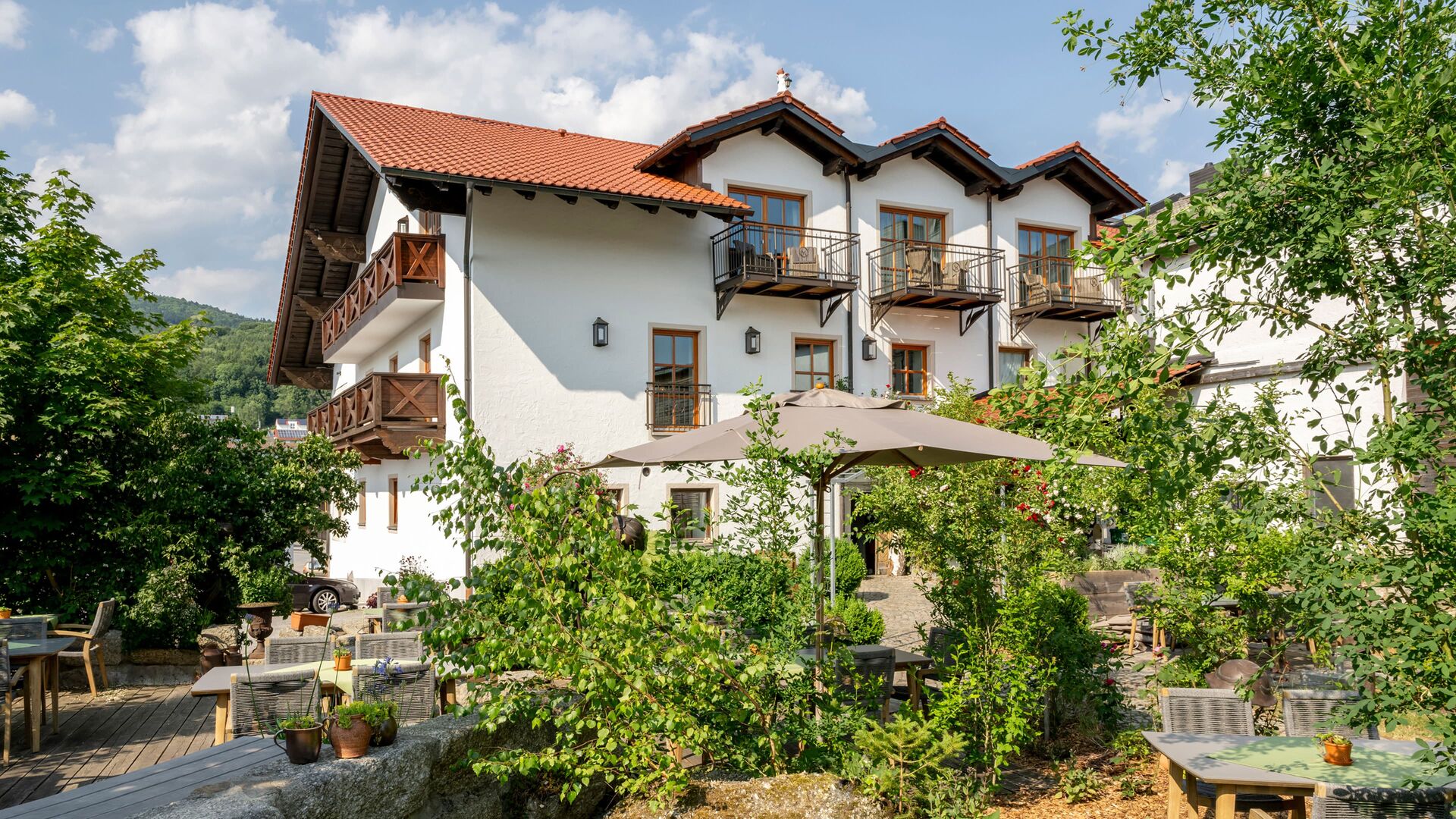 Der traditionsreiche Gasthof Kammbräu inmitten grüner Bäume und blühender Gärten