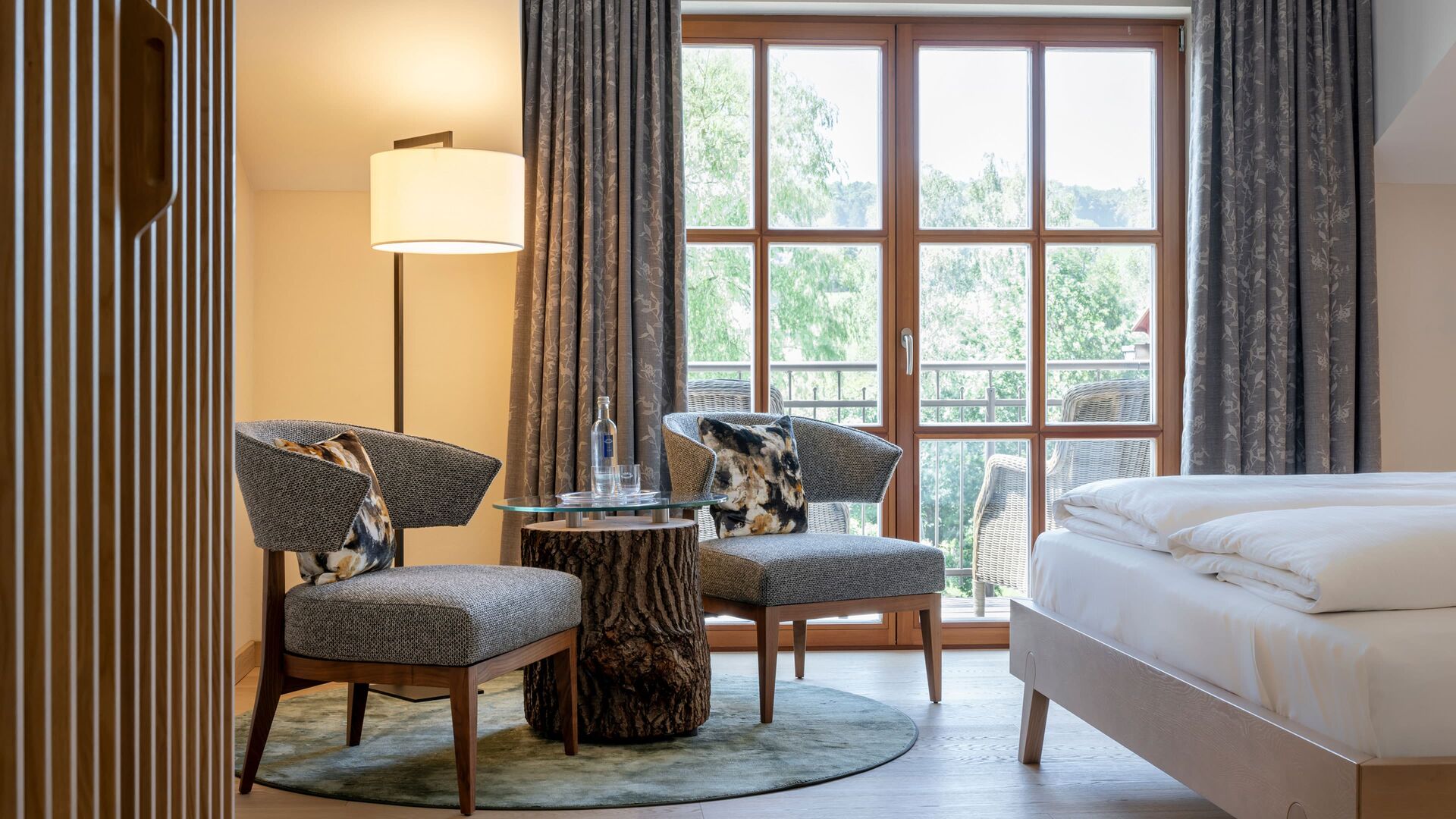 Helles Doppelzimmer mit gemütlicher Sitzecke und großem Fenster mit Ausblick ins Grüne