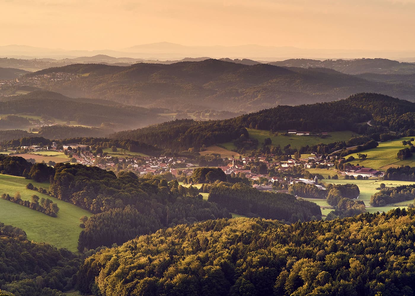 Weitblick bei Sonnenaufgang über bewaldete Hügel im Bayerischen Wald