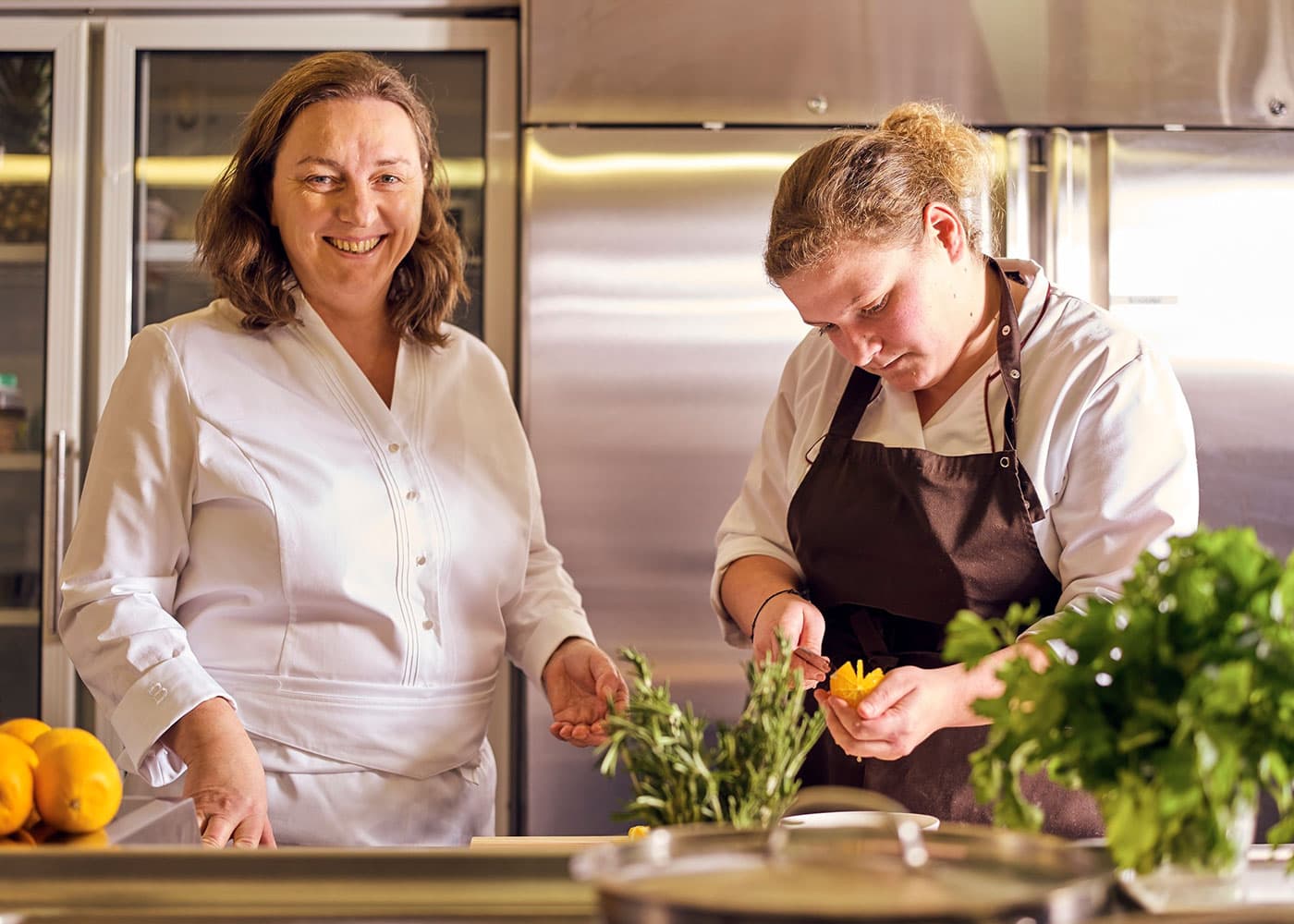 Sigrid Kamm mit ihrer Mitarbeiterin bereiten regionale Speisen mit frischen Kräutern in der Küche des Kammbräu zu